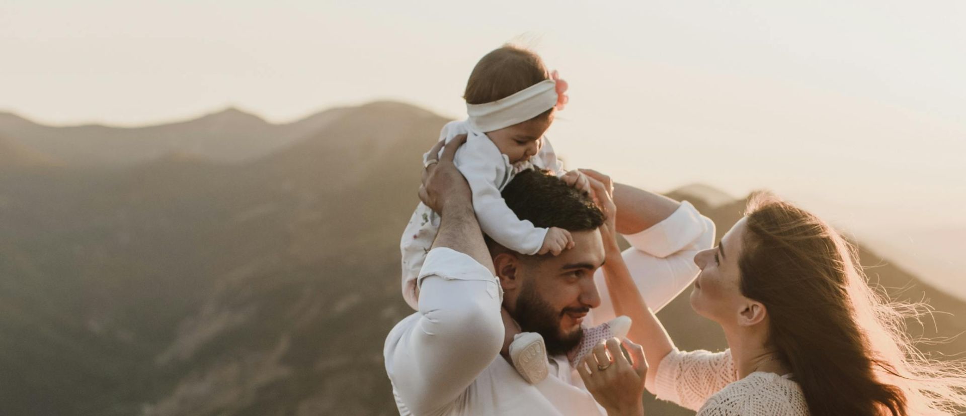 Young couple with baby enjoying a scenic outdoor sunset hike.