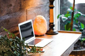 A cozy home office setup featuring a laptop, salt lamp, and plants on a wooden desk. Ideal for remote work.