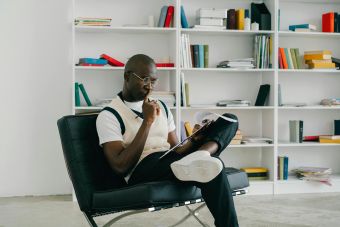 Contemplative African American man reading in a stylish library setting.